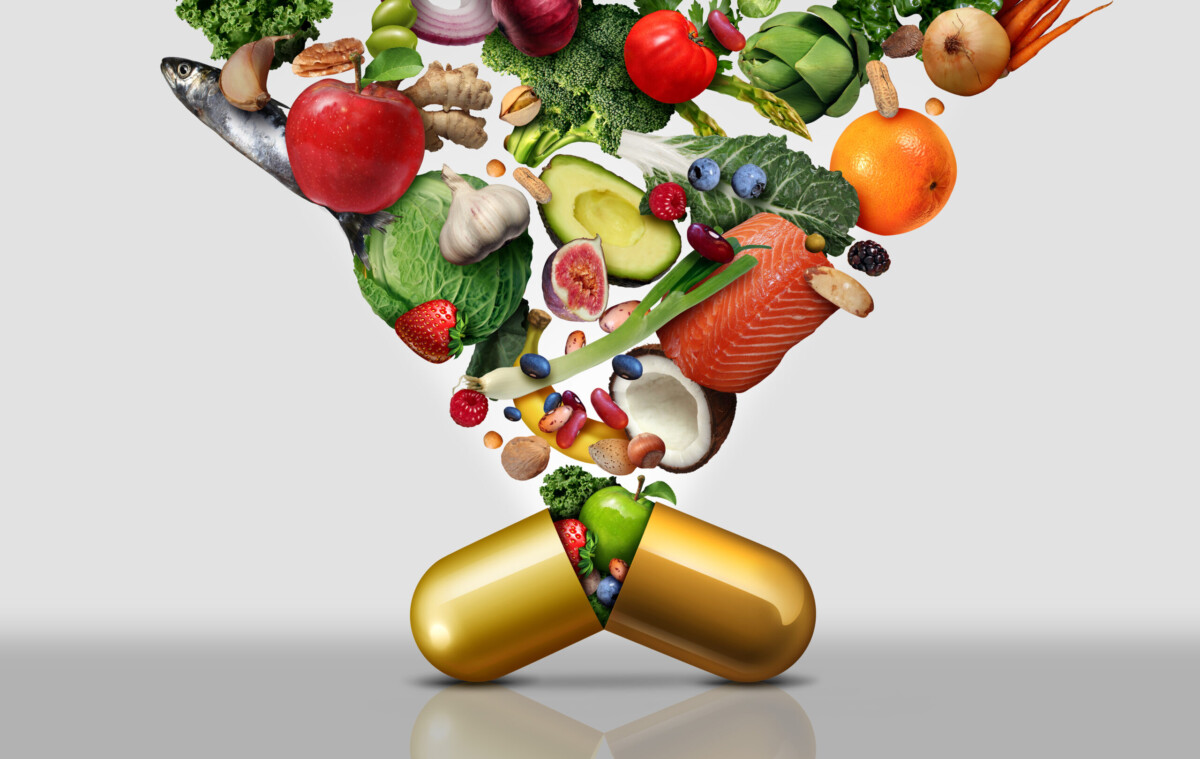 Een gouden capsule splijt open, waardoor een verscheidenheid aan verse voedingsmiddelen vrijkomt, waaronder fruit, groenten, vis, noten en bessen, ter illustratie van het concept van voeding of supplementen afgeleid van hele voedingsmiddelen.